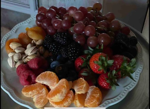 A colorful platter of assorted fruits, including grapes, strawberries, blackberries, raspberries, blueberries, and mandarin slices.