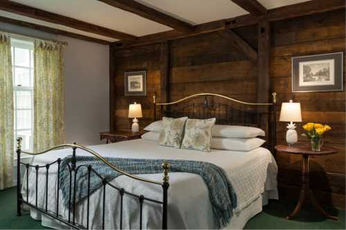 Cozy bedroom with a metal bed, decorative pillows, wooden walls, and soft lighting from bedside lamps.