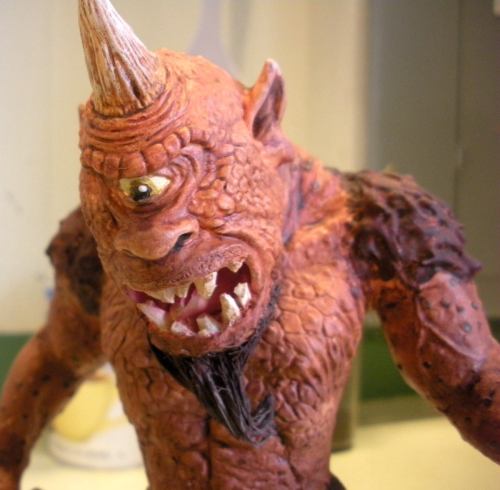 A detailed figure of a monstrous creature with one eye, sharp teeth, and a horn on its head, showcasing textured skin.