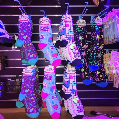 Colorful socks displayed on a rack, featuring various playful patterns and designs.