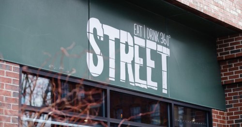 Sign for "STREET" restaurant with the tagline "EAT | DRINK 360°" on a brick building exterior.