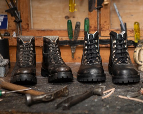 A pair of rugged boots on a workbench surrounded by tools, showcasing their sturdy design and craftsmanship.