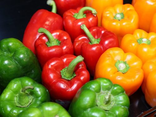 A colorful assortment of bell peppers in red, green, and yellow arranged closely together.