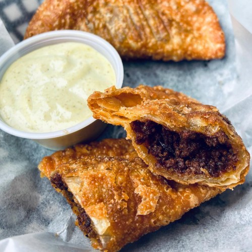 Crispy fried empanadas with a savory filling, served with a creamy dipping sauce on the side.