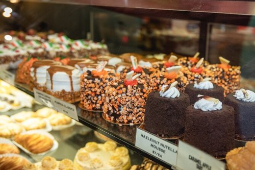A display case filled with various delicious cakes and desserts, including mousse and chocolate treats.
