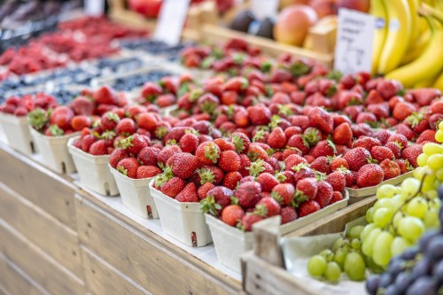 A vibrant display of fresh strawberries, blueberries, and grapes in baskets at a market.
