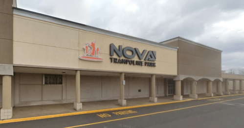 Exterior of NOVA Trampoline Park building with a sign, cloudy sky, and empty parking lot.