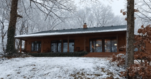 A cozy wooden house surrounded by snow-covered trees on a winter day.