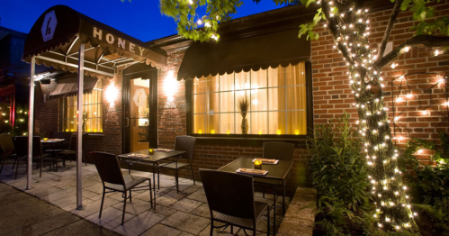 Cozy restaurant exterior at night, featuring outdoor seating and warm lighting with decorative string lights.