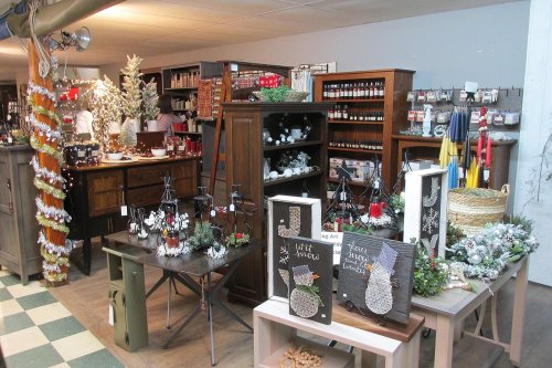 A cozy shop display featuring holiday decorations, candles, and festive crafts on wooden tables and shelves.