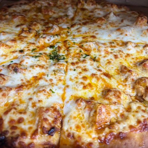 A close-up of a cheesy pizza with golden crust and toppings, sliced into equal pieces.