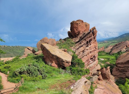 A rocky formation surrounded by green vegetation under a cloudy sky, showcasing natural geological features.