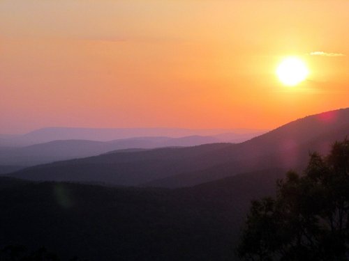 A serene sunset over rolling mountains, with soft hues of orange and purple in the sky.