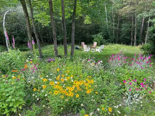 A vibrant garden filled with colorful flowers, featuring a cozy seating area surrounded by trees.