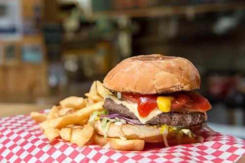 A juicy hamburger with cheese, lettuce, ketchup, and mustard, served with a side of crispy French fries on a checkered plate.