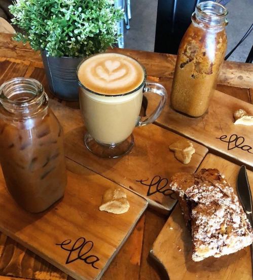 A cozy café scene featuring a latte, iced coffee, and a pastry on wooden boards with a small plant in the background.