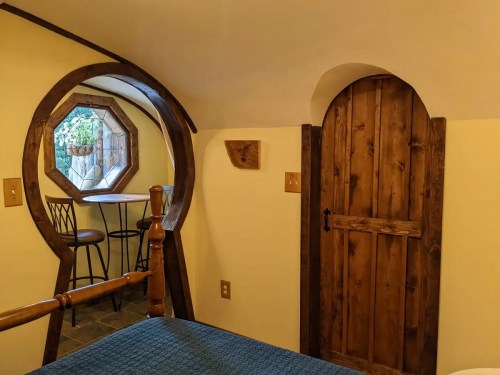 Cozy interior featuring a round window, wooden door, and a small table with chairs in a warm, inviting space.