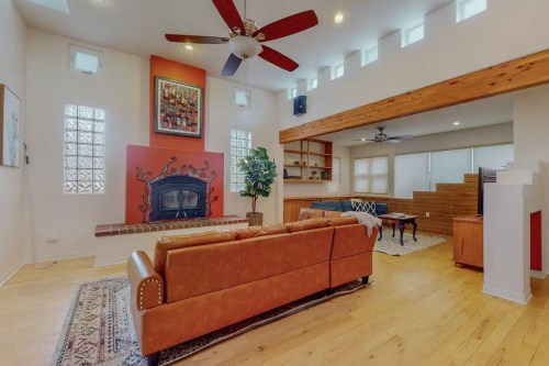 Spacious living room with a brown leather sofa, wooden accents, and a cozy fireplace, featuring large windows and a modern design.