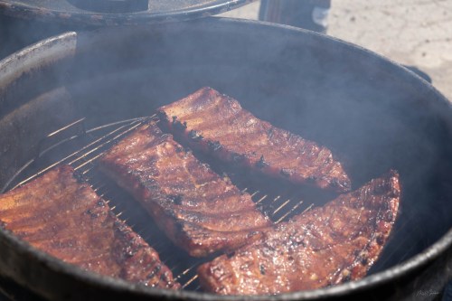 Smoky barbecue ribs sizzling on a grill, glistening with a rich glaze.