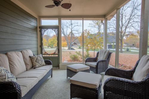Cozy screened porch with wicker furniture, overlooking a colorful autumn landscape.