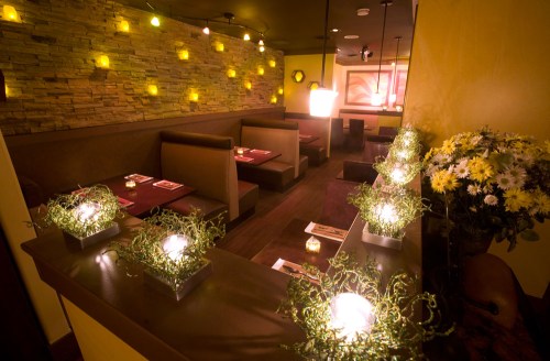 Cozy restaurant interior with stone walls, dim lighting, and floral centerpieces on tables.