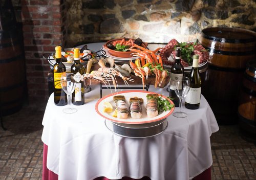 A beautifully arranged seafood platter with wine, featuring crab, shrimp, and various shellfish on a table.