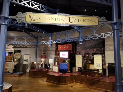 Exhibit titled "Mechanical Universe" featuring various historical machines and displays in a museum setting.