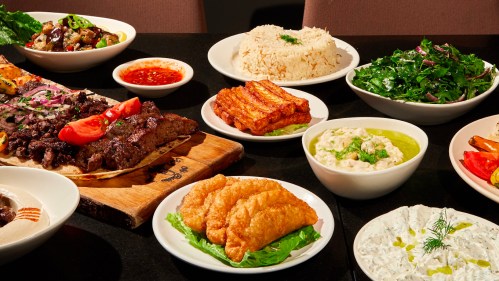 A variety of dishes including grilled meats, rice, salads, and sauces arranged on a table.
