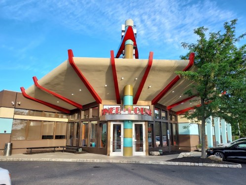 A colorful, retro-style building with a distinctive roof and large windows, featuring the sign "INN & LOUNGE."