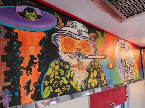 Colorful mural featuring a cool owl in sunglasses, smoking, with a UFO and playful cats in a vibrant, whimsical style.