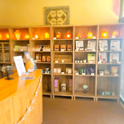 A cozy shop interior featuring wooden shelves filled with wellness products and a curved reception desk.