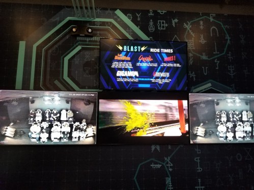Screens displaying ride times and images from an amusement park, featuring various attractions and a colorful splash.