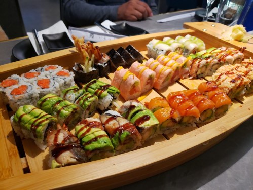 A wooden platter filled with various sushi rolls, including colorful toppings and garnishes.