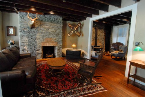 Cozy living room with stone walls, a fireplace, leather sofa, wooden table, and rustic decor.