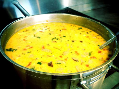 A large pot of creamy soup with vegetables and herbs, simmering on a stove.