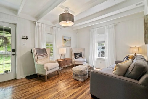 Cozy living room with two armchairs, a sofa, a coffee table, and large windows letting in natural light.