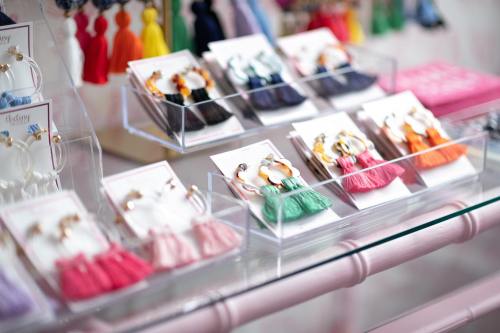 Colorful earrings displayed in clear boxes, featuring various styles and tassel designs on a glass shelf.