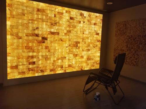 A cozy room featuring a glowing salt wall and a reclining chair, creating a warm and relaxing atmosphere.