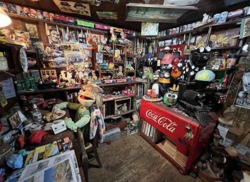 A cluttered room filled with vintage memorabilia, puppets, and collectibles, creating a nostalgic atmosphere.