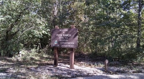 Welcome sign for Peck Ranch, marked as a Missouri Conservation Department trail, surrounded by trees.