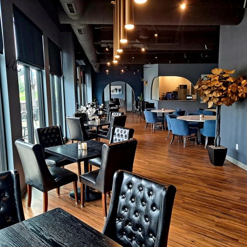 Modern restaurant interior featuring dark walls, wooden floors, elegant seating, and stylish decor.