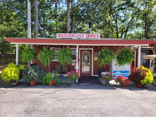A charming office building with a sign reading "Wanderlust Office," surrounded by vibrant flowers and greenery.