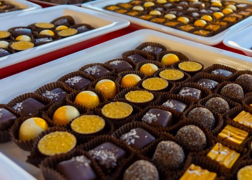 A variety of beautifully arranged chocolates in trays, featuring different shapes and toppings.