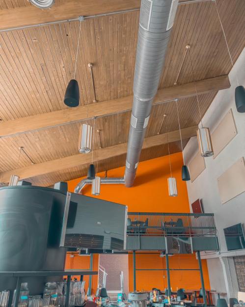 Interior of a modern space featuring wooden beams, industrial lighting, and an orange accent wall.