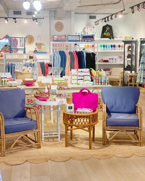 A bright retail space featuring two blue chairs, a table, and colorful merchandise on shelves in the background.