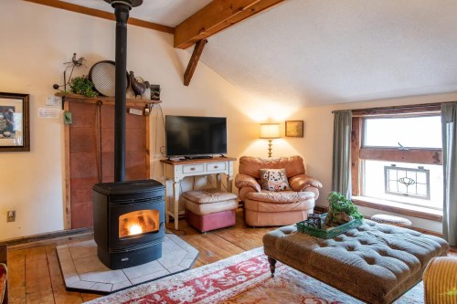 Cozy living room with a wood stove, comfortable seating, a TV, and a window with natural light.
