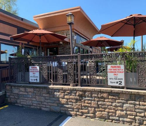 Outdoor dining area with umbrellas, featuring signs for takeout and curbside pickup parking spots.