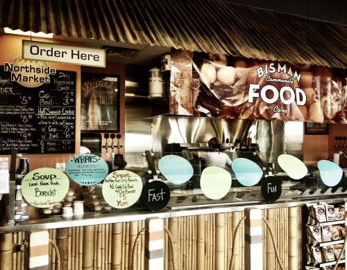 A food counter with a menu board, colorful signs, and a tropical decor theme, inviting customers to order.