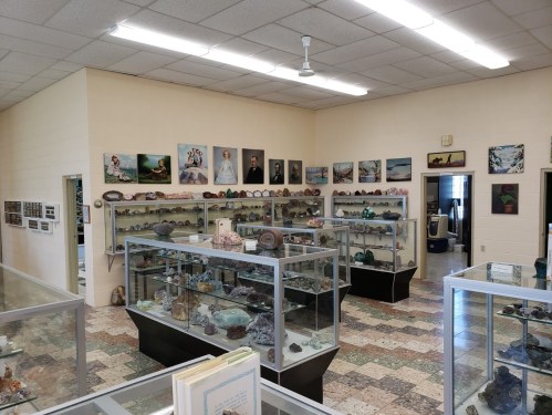 A museum display featuring various rocks and minerals in glass cases, with photographs on the walls.