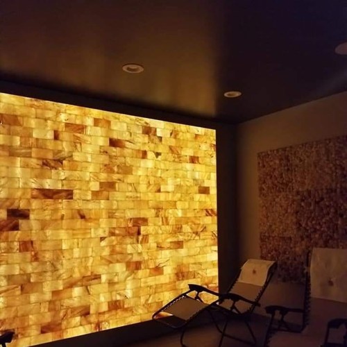 A cozy room featuring a warm, illuminated salt wall and two lounge chairs for relaxation.